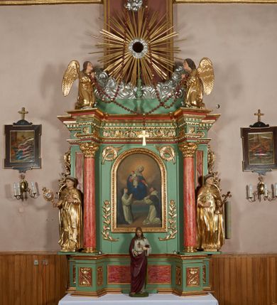 Zdjęcie nr 1: Ołtarz przyścienny, architektoniczny, jednoosiowy, jednokondygnacyjny ze zwieńczeniem i uszakami. Mensa kamienna ustawiona na dwóch niskich kolumnach o impostowych kapitelach. Nastawa drewniana, ujęta korynckimi kolumnami ustawionymi ukośnie na wysokich postumentach. Dźwigają one pełne, wyłamane na ich osiach belkowanie. Fryz jest dekorowany akantem, jajownikiem oraz kostkowaniem; gzyms silnie wystający, profilowany. Na osi kolumn ustawione pełnoplastyczne figury klęczących aniołów w złoconych szatach. W kondygnacji obraz Matki Boskiej Różańcowej w kształcie stojącego prostokąta zamkniętego półkoliście, otoczony wieńcami laurowymi z przetkniętymi liśćmi palmy oraz różami. Po bokach kolumn ustawione pełnoplastyczne, polichromowane i złocone figury św. Jacka (z lewej) trzymającego monstrancję i figurę Matki Boskiej tzw. Jackowej oraz św. Dominika (z prawej) trzymającego krucyfiks i księgę. Kondygnacja ujęta jest ażurowymi akantowymi uszami. W zwieńczeniu gloria promienista powyżej srebrzonych obłoków. Nad nią pełnoplastyczna figura anioła stojącego na chmurze i podtrzymującego różaniec. Struktura ołtarza w kolorze jasnozielonym, wypełnienia płycin, trzony kolumn oraz elementy gzymsu jasnoczerwone, marmoryzowane; ornamenty złocone.