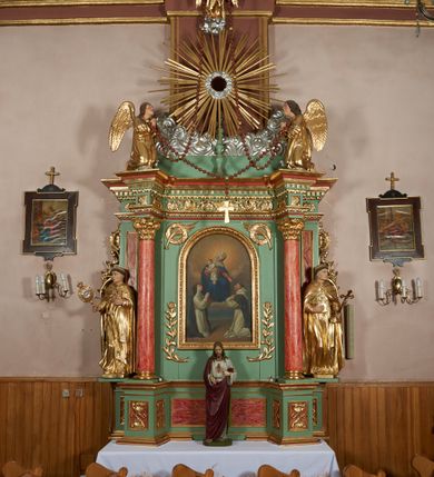 Zdjęcie nr 2: Ołtarz przyścienny, architektoniczny, jednoosiowy, jednokondygnacyjny ze zwieńczeniem i uszakami. Mensa kamienna ustawiona na dwóch niskich kolumnach o impostowych kapitelach. Nastawa drewniana, ujęta korynckimi kolumnami ustawionymi ukośnie na wysokich postumentach. Dźwigają one pełne, wyłamane na ich osiach belkowanie. Fryz jest dekorowany akantem, jajownikiem oraz kostkowaniem; gzyms silnie wystający, profilowany. Na osi kolumn ustawione pełnoplastyczne figury klęczących aniołów w złoconych szatach. W kondygnacji obraz Matki Boskiej Różańcowej w kształcie stojącego prostokąta zamkniętego półkoliście, otoczony wieńcami laurowymi z przetkniętymi liśćmi palmy oraz różami. Po bokach kolumn ustawione pełnoplastyczne, polichromowane i złocone figury św. Jacka (z lewej) trzymającego monstrancję i figurę Matki Boskiej tzw. Jackowej oraz św. Dominika (z prawej) trzymającego krucyfiks i księgę. Kondygnacja ujęta jest ażurowymi akantowymi uszami. W zwieńczeniu gloria promienista powyżej srebrzonych obłoków. Nad nią pełnoplastyczna figura anioła stojącego na chmurze i podtrzymującego różaniec. Struktura ołtarza w kolorze jasnozielonym, wypełnienia płycin, trzony kolumn oraz elementy gzymsu jasnoczerwone, marmoryzowane; ornamenty złocone.