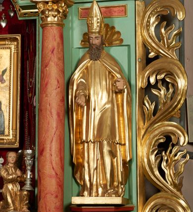 Zdjęcie nr 10: Ołtarz przyścienny, architektoniczny, trójosiowy, jednokondygnacyjny ze zwieńczeniem i uszakami. Mensa w typie sarkofagowym na niewielkim prostopadłościennym postumencie. Tabernakulum drewniane, architektoniczne, ujęte złoconymi kolumienkami dźwigającymi wyłamane i wyniesione belkowanie. Na drzwiczkach płaskorzeźbione przedstawienie kielicha z hostią. Nastawa drewniana ujęta korynckimi kolumnami ustawionymi na wysokich postumentach. Dźwigają one pełne, wyłamane na osiach kolumn i półkoliście wyniesione na osi środkowej ołtarza belkowanie. Fryz dekorowany rozetami oraz uskrzydloną główką anielską. Powyżej odcinki przyczółka, na których ustawione pełnoplastyczne figury świętych wojowników. W polu środkowym nisza zamknięta łukiem półkolistym nadwieszonym mieszcząca obraz Matki Boskiej Nieustającej Pomocy. W osiach bocznych ustawione na tle płycin pełnoplastyczne figury świętych biskupów w złoconych szatach oraz akantowe, ażurowe uszaki utworzone z wici akantowej. W zwieńczeniu obraz „Nawiedzenie Najświętszej Marii Panny” w kształcie stojącego prostokąta ujęty ażurowymi uszami utworzonymi z ornamentu mażowinowo-chrząstkowego, i winorośli. Powyżej, analogicznie, mniejszy obraz „Trójca Święta” w kształcie prostokąta stojącego o ściętych górnych narożach, zwieńczonego krzyżem równoramiennym. Struktura ołtarza w kolorze jasnozielonym, wypełnienia płycin, trzony kolumn oraz elementy gzymsu jasnoczerwone, marmoryzowane; ornamenty złocone.