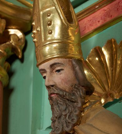 Zdjęcie nr 11: Ołtarz przyścienny, architektoniczny, trójosiowy, jednokondygnacyjny ze zwieńczeniem i uszakami. Mensa w typie sarkofagowym na niewielkim prostopadłościennym postumencie. Tabernakulum drewniane, architektoniczne, ujęte złoconymi kolumienkami dźwigającymi wyłamane i wyniesione belkowanie. Na drzwiczkach płaskorzeźbione przedstawienie kielicha z hostią. Nastawa drewniana ujęta korynckimi kolumnami ustawionymi na wysokich postumentach. Dźwigają one pełne, wyłamane na osiach kolumn i półkoliście wyniesione na osi środkowej ołtarza belkowanie. Fryz dekorowany rozetami oraz uskrzydloną główką anielską. Powyżej odcinki przyczółka, na których ustawione pełnoplastyczne figury świętych wojowników. W polu środkowym nisza zamknięta łukiem półkolistym nadwieszonym mieszcząca obraz Matki Boskiej Nieustającej Pomocy. W osiach bocznych ustawione na tle płycin pełnoplastyczne figury świętych biskupów w złoconych szatach oraz akantowe, ażurowe uszaki utworzone z wici akantowej. W zwieńczeniu obraz „Nawiedzenie Najświętszej Marii Panny” w kształcie stojącego prostokąta ujęty ażurowymi uszami utworzonymi z ornamentu mażowinowo-chrząstkowego, i winorośli. Powyżej, analogicznie, mniejszy obraz „Trójca Święta” w kształcie prostokąta stojącego o ściętych górnych narożach, zwieńczonego krzyżem równoramiennym. Struktura ołtarza w kolorze jasnozielonym, wypełnienia płycin, trzony kolumn oraz elementy gzymsu jasnoczerwone, marmoryzowane; ornamenty złocone.