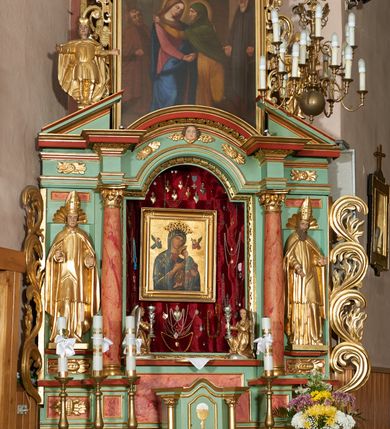 Zdjęcie nr 3: Ołtarz przyścienny, architektoniczny, trójosiowy, jednokondygnacyjny ze zwieńczeniem i uszakami. Mensa w typie sarkofagowym na niewielkim prostopadłościennym postumencie. Tabernakulum drewniane, architektoniczne, ujęte złoconymi kolumienkami dźwigającymi wyłamane i wyniesione belkowanie. Na drzwiczkach płaskorzeźbione przedstawienie kielicha z hostią. Nastawa drewniana ujęta korynckimi kolumnami ustawionymi na wysokich postumentach. Dźwigają one pełne, wyłamane na osiach kolumn i półkoliście wyniesione na osi środkowej ołtarza belkowanie. Fryz dekorowany rozetami oraz uskrzydloną główką anielską. Powyżej odcinki przyczółka, na których ustawione pełnoplastyczne figury świętych wojowników. W polu środkowym nisza zamknięta łukiem półkolistym nadwieszonym mieszcząca obraz Matki Boskiej Nieustającej Pomocy. W osiach bocznych ustawione na tle płycin pełnoplastyczne figury świętych biskupów w złoconych szatach oraz akantowe, ażurowe uszaki utworzone z wici akantowej. W zwieńczeniu obraz „Nawiedzenie Najświętszej Marii Panny” w kształcie stojącego prostokąta ujęty ażurowymi uszami utworzonymi z ornamentu mażowinowo-chrząstkowego, i winorośli. Powyżej, analogicznie, mniejszy obraz „Trójca Święta” w kształcie prostokąta stojącego o ściętych górnych narożach, zwieńczonego krzyżem równoramiennym. Struktura ołtarza w kolorze jasnozielonym, wypełnienia płycin, trzony kolumn oraz elementy gzymsu jasnoczerwone, marmoryzowane; ornamenty złocone.