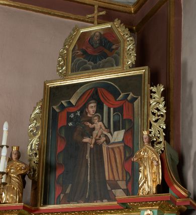 Zdjęcie nr 8: Ołtarz przyścienny, architektoniczny, jednoosiowy, jednokondygnacyjny ze zwieńczeniem; uszaty. Mensa w typie sarkofagowym na niewielkim prostopadłościennym postumencie. Tabernakulum drewniane, architektoniczne, ujęte parami złoconych kolumienek, na osi których odcinki belkowania i spiralnie zwinięte akantowe woluty oraz kanelowanymi pilastrami. W zwieńczeniu motyw podwieszonej kotary oraz lambrekin. Na drzwiczkach płaskorzeźbione przedstawienie kielicha z hostią. Nastawa drewniana, ujęta korynckimi kolumnami ustawionymi na wysokich postumentach zdobionych plakietami roślinnymi. Dźwigają one pełne, wyłamane na ich osiach belkowanie. Fryz wysuniętych części dekorowany rozetami, silnie wystający gzyms zdobiony akantem. Powyżej odcinki przyczółka, na tle których ustawione pełnoplastyczne figury świętych dziewic w koronach i złoconych szatach. W kondygnacji pierwszej nisza zamknięta łukiem półkolistym nadwieszonym, mieszcząca obraz św. Mikołaja. Kondygnacja ujęta ażurowymi akantowymi uszakami. W zwieńczeniu przedstawienie św. Antoniego Padewskiego w formie stojącego prostokąta, ujętego ażurowymi uszakami utworzonymi z wici akantu. Powyżej, analogicznie, mniejsze ujęcie Boga Ojca w kształcie stojącego prostokąta o ściętych górnych narożach, zwieńczonego krzyżem równoramiennym. Struktura ołtarza w kolorze jasnozielonym, wypełnienia płycin, trzony kolumn oraz elementy gzymsu jasnoczerwone; ornamenty złocone.
