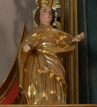 Zdjęcie nr 10: Ołtarz przyścienny, architektoniczny, jednoosiowy, jednokondygnacyjny ze zwieńczeniem; uszaty. Mensa w typie sarkofagowym na niewielkim prostopadłościennym postumencie. Tabernakulum drewniane, architektoniczne, ujęte parami złoconych kolumienek, na osi których odcinki belkowania i spiralnie zwinięte akantowe woluty oraz kanelowanymi pilastrami. W zwieńczeniu motyw podwieszonej kotary oraz lambrekin. Na drzwiczkach płaskorzeźbione przedstawienie kielicha z hostią. Nastawa drewniana, ujęta korynckimi kolumnami ustawionymi na wysokich postumentach zdobionych plakietami roślinnymi. Dźwigają one pełne, wyłamane na ich osiach belkowanie. Fryz wysuniętych części dekorowany rozetami, silnie wystający gzyms zdobiony akantem. Powyżej odcinki przyczółka, na tle których ustawione pełnoplastyczne figury świętych dziewic w koronach i złoconych szatach. W kondygnacji pierwszej nisza zamknięta łukiem półkolistym nadwieszonym, mieszcząca obraz św. Mikołaja. Kondygnacja ujęta ażurowymi akantowymi uszakami. W zwieńczeniu przedstawienie św. Antoniego Padewskiego w formie stojącego prostokąta, ujętego ażurowymi uszakami utworzonymi z wici akantu. Powyżej, analogicznie, mniejsze ujęcie Boga Ojca w kształcie stojącego prostokąta o ściętych górnych narożach, zwieńczonego krzyżem równoramiennym. Struktura ołtarza w kolorze jasnozielonym, wypełnienia płycin, trzony kolumn oraz elementy gzymsu jasnoczerwone; ornamenty złocone.