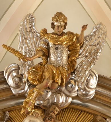 Zdjęcie nr 8: Ołtarz architektoniczny, jednokondygnacyjny, jednoosiowy, ze zwieńczeniem. Nastawa zbudowana na kamiennym, wysokim cokole, lekko wklęsła, ujęta zwielokrotnionymi pilastrami kompozytowymi o kanelowanych trzonach i zewnętrznymi, nieznacznie cofniętymi kolumnami, podtrzymującymi wyłamujące się nad nimi belkowanie. Po bokach karbowane taśmy z motywem liści akantu. W centrum obraz "Przemienienie Pańskie". Nad pilastrami klęczące na obłokach uskrzydlone, adorujące anioły. Zwieńczenie o łukowato wygiętej podstawie i wklęsłych nieznacznie bokach, zwieńczone wyłamanym ku górze gzymsem zakończonym po bokach wolutami. W zwieńczenie wkomponowana okazała gloria promienista, z figurą Boga Ojca siedzącego w chmurach, Gołębicą Ducha Świętego i ukazaną na tle gzymsu postacią Archanioła Michała, ukazanego w zbroi, płaszczu na ramionach i w hełmie na głowie z mieczem w prawej dłoni. Na belkowaniu okazały kartusz ujęty puklowaną wstęgą i zwieńczony muszlą, z malowanym na srebrnym tle napisem: "CHRISTO / TRANSFIGURATO / Hic est Filius meus dilectus / in quo mihi bene complacui / ipsum audite. / Matth: c. 77". Na ścianach prezbiterium, przed ołtarzem, na konsolach dwie figury św. Andrzej i św. Mateusz (?). Nastawa w całości złocona, partiami srebrzona (chmury, skrzydła aniołów, rama zwieńczenia, wstęga regencyjna po bokach), partie cokołu i fryzu z imitacją marmoryzacji.   

