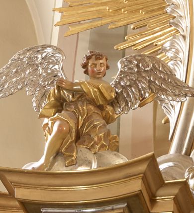 Zdjęcie nr 10: Ołtarz architektoniczny, jednokondygnacyjny, jednoosiowy, ze zwieńczeniem. Nastawa zbudowana na kamiennym, wysokim cokole, lekko wklęsła, ujęta zwielokrotnionymi pilastrami kompozytowymi o kanelowanych trzonach i zewnętrznymi, nieznacznie cofniętymi kolumnami, podtrzymującymi wyłamujące się nad nimi belkowanie. Po bokach karbowane taśmy z motywem liści akantu. W centrum obraz "Przemienienie Pańskie". Nad pilastrami klęczące na obłokach uskrzydlone, adorujące anioły. Zwieńczenie o łukowato wygiętej podstawie i wklęsłych nieznacznie bokach, zwieńczone wyłamanym ku górze gzymsem zakończonym po bokach wolutami. W zwieńczenie wkomponowana okazała gloria promienista, z figurą Boga Ojca siedzącego w chmurach, Gołębicą Ducha Świętego i ukazaną na tle gzymsu postacią Archanioła Michała, ukazanego w zbroi, płaszczu na ramionach i w hełmie na głowie z mieczem w prawej dłoni. Na belkowaniu okazały kartusz ujęty puklowaną wstęgą i zwieńczony muszlą, z malowanym na srebrnym tle napisem: "CHRISTO / TRANSFIGURATO / Hic est Filius meus dilectus / in quo mihi bene complacui / ipsum audite. / Matth: c. 77". Na ścianach prezbiterium, przed ołtarzem, na konsolach dwie figury św. Andrzej i św. Mateusz (?). Nastawa w całości złocona, partiami srebrzona (chmury, skrzydła aniołów, rama zwieńczenia, wstęga regencyjna po bokach), partie cokołu i fryzu z imitacją marmoryzacji.   

