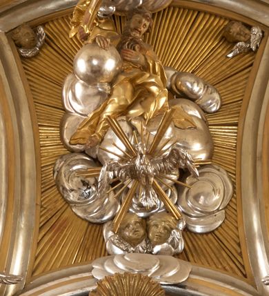 Zdjęcie nr 6: Ołtarz architektoniczny, jednokondygnacyjny, jednoosiowy, ze zwieńczeniem. Nastawa zbudowana na kamiennym, wysokim cokole, lekko wklęsła, ujęta zwielokrotnionymi pilastrami kompozytowymi o kanelowanych trzonach i zewnętrznymi, nieznacznie cofniętymi kolumnami, podtrzymującymi wyłamujące się nad nimi belkowanie. Po bokach karbowane taśmy z motywem liści akantu. W centrum obraz &quot;Przemienienie Pańskie&quot;. Nad pilastrami klęczące na obłokach uskrzydlone, adorujące anioły. Zwieńczenie o łukowato wygiętej podstawie i wklęsłych nieznacznie bokach, zwieńczone wyłamanym ku górze gzymsem zakończonym po bokach wolutami. W zwieńczenie wkomponowana okazała gloria promienista, z figurą Boga Ojca siedzącego w chmurach, Gołębicą Ducha Świętego i ukazaną na tle gzymsu postacią Archanioła Michała, ukazanego w zbroi, płaszczu na ramionach i w hełmie na głowie z mieczem w prawej dłoni. Na belkowaniu okazały kartusz ujęty puklowaną wstęgą i zwieńczony muszlą, z malowanym na srebrnym tle napisem: &quot;CHRISTO / TRANSFIGURATO / Hic est Filius meus dilectus / in quo mihi bene complacui / ipsum audite. / Matth: c. 77&quot;. Na ścianach prezbiterium, przed ołtarzem, na konsolach dwie figury św. Andrzej i św. Mateusz (?). Nastawa w całości złocona, partiami srebrzona (chmury, skrzydła aniołów, rama zwieńczenia, wstęga regencyjna po bokach), partie cokołu i fryzu z imitacją marmoryzacji.   

