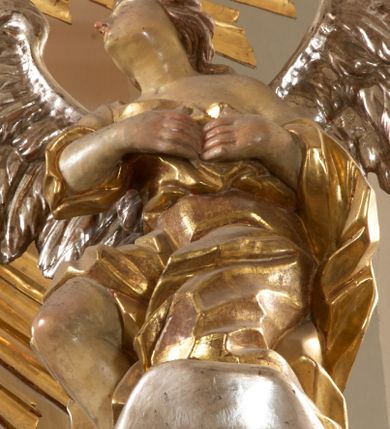 Zdjęcie nr 11: Ołtarz architektoniczny, jednokondygnacyjny, jednoosiowy, ze zwieńczeniem. Nastawa zbudowana na kamiennym, wysokim cokole, lekko wklęsła, ujęta zwielokrotnionymi pilastrami kompozytowymi o kanelowanych trzonach i zewnętrznymi, nieznacznie cofniętymi kolumnami, podtrzymującymi wyłamujące się nad nimi belkowanie. Po bokach karbowane taśmy z motywem liści akantu. W centrum obraz &quot;Przemienienie Pańskie&quot;. Nad pilastrami klęczące na obłokach uskrzydlone, adorujące anioły. Zwieńczenie o łukowato wygiętej podstawie i wklęsłych nieznacznie bokach, zwieńczone wyłamanym ku górze gzymsem zakończonym po bokach wolutami. W zwieńczenie wkomponowana okazała gloria promienista, z figurą Boga Ojca siedzącego w chmurach, Gołębicą Ducha Świętego i ukazaną na tle gzymsu postacią Archanioła Michała, ukazanego w zbroi, płaszczu na ramionach i w hełmie na głowie z mieczem w prawej dłoni. Na belkowaniu okazały kartusz ujęty puklowaną wstęgą i zwieńczony muszlą, z malowanym na srebrnym tle napisem: &quot;CHRISTO / TRANSFIGURATO / Hic est Filius meus dilectus / in quo mihi bene complacui / ipsum audite. / Matth: c. 77&quot;. Na ścianach prezbiterium, przed ołtarzem, na konsolach dwie figury św. Andrzej i św. Mateusz (?). Nastawa w całości złocona, partiami srebrzona (chmury, skrzydła aniołów, rama zwieńczenia, wstęga regencyjna po bokach), partie cokołu i fryzu z imitacją marmoryzacji.   

