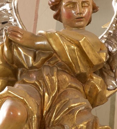 Zdjęcie nr 13: Ołtarz architektoniczny, jednokondygnacyjny, jednoosiowy, ze zwieńczeniem. Nastawa zbudowana na kamiennym, wysokim cokole, lekko wklęsła, ujęta zwielokrotnionymi pilastrami kompozytowymi o kanelowanych trzonach i zewnętrznymi, nieznacznie cofniętymi kolumnami, podtrzymującymi wyłamujące się nad nimi belkowanie. Po bokach karbowane taśmy z motywem liści akantu. W centrum obraz "Przemienienie Pańskie". Nad pilastrami klęczące na obłokach uskrzydlone, adorujące anioły. Zwieńczenie o łukowato wygiętej podstawie i wklęsłych nieznacznie bokach, zwieńczone wyłamanym ku górze gzymsem zakończonym po bokach wolutami. W zwieńczenie wkomponowana okazała gloria promienista, z figurą Boga Ojca siedzącego w chmurach, Gołębicą Ducha Świętego i ukazaną na tle gzymsu postacią Archanioła Michała, ukazanego w zbroi, płaszczu na ramionach i w hełmie na głowie z mieczem w prawej dłoni. Na belkowaniu okazały kartusz ujęty puklowaną wstęgą i zwieńczony muszlą, z malowanym na srebrnym tle napisem: "CHRISTO / TRANSFIGURATO / Hic est Filius meus dilectus / in quo mihi bene complacui / ipsum audite. / Matth: c. 77". Na ścianach prezbiterium, przed ołtarzem, na konsolach dwie figury św. Andrzej i św. Mateusz (?). Nastawa w całości złocona, partiami srebrzona (chmury, skrzydła aniołów, rama zwieńczenia, wstęga regencyjna po bokach), partie cokołu i fryzu z imitacją marmoryzacji.   

