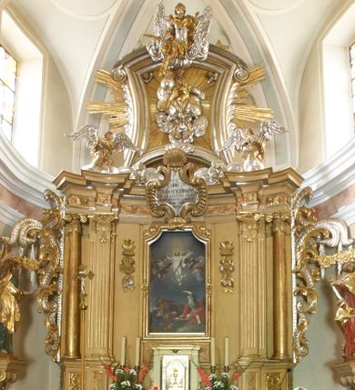 Zdjęcie nr 1: Ołtarz architektoniczny, jednokondygnacyjny, jednoosiowy, ze zwieńczeniem. Nastawa zbudowana na kamiennym, wysokim cokole, lekko wklęsła, ujęta zwielokrotnionymi pilastrami kompozytowymi o kanelowanych trzonach i zewnętrznymi, nieznacznie cofniętymi kolumnami, podtrzymującymi wyłamujące się nad nimi belkowanie. Po bokach karbowane taśmy z motywem liści akantu. W centrum obraz "Przemienienie Pańskie". Nad pilastrami klęczące na obłokach uskrzydlone, adorujące anioły. Zwieńczenie o łukowato wygiętej podstawie i wklęsłych nieznacznie bokach, zwieńczone wyłamanym ku górze gzymsem zakończonym po bokach wolutami. W zwieńczenie wkomponowana okazała gloria promienista, z figurą Boga Ojca siedzącego w chmurach, Gołębicą Ducha Świętego i ukazaną na tle gzymsu postacią Archanioła Michała, ukazanego w zbroi, płaszczu na ramionach i w hełmie na głowie z mieczem w prawej dłoni. Na belkowaniu okazały kartusz ujęty puklowaną wstęgą i zwieńczony muszlą, z malowanym na srebrnym tle napisem: "CHRISTO / TRANSFIGURATO / Hic est Filius meus dilectus / in quo mihi bene complacui / ipsum audite. / Matth: c. 77". Na ścianach prezbiterium, przed ołtarzem, na konsolach dwie figury św. Andrzej i św. Mateusz (?). Nastawa w całości złocona, partiami srebrzona (chmury, skrzydła aniołów, rama zwieńczenia, wstęga regencyjna po bokach), partie cokołu i fryzu z imitacją marmoryzacji.   


