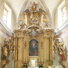 Zdjęcie nr 1: Ołtarz architektoniczny, jednokondygnacyjny, jednoosiowy, ze zwieńczeniem. Nastawa zbudowana na kamiennym, wysokim cokole, lekko wklęsła, ujęta zwielokrotnionymi pilastrami kompozytowymi o kanelowanych trzonach i zewnętrznymi, nieznacznie cofniętymi kolumnami, podtrzymującymi wyłamujące się nad nimi belkowanie. Po bokach karbowane taśmy z motywem liści akantu. W centrum obraz "Przemienienie Pańskie". Nad pilastrami klęczące na obłokach uskrzydlone, adorujące anioły. Zwieńczenie o łukowato wygiętej podstawie i wklęsłych nieznacznie bokach, zwieńczone wyłamanym ku górze gzymsem zakończonym po bokach wolutami. W zwieńczenie wkomponowana okazała gloria promienista, z figurą Boga Ojca siedzącego w chmurach, Gołębicą Ducha Świętego i ukazaną na tle gzymsu postacią Archanioła Michała, ukazanego w zbroi, płaszczu na ramionach i w hełmie na głowie z mieczem w prawej dłoni. Na belkowaniu okazały kartusz ujęty puklowaną wstęgą i zwieńczony muszlą, z malowanym na srebrnym tle napisem: "CHRISTO / TRANSFIGURATO / Hic est Filius meus dilectus / in quo mihi bene complacui / ipsum audite. / Matth: c. 77". Na ścianach prezbiterium, przed ołtarzem, na konsolach dwie figury św. Andrzej i św. Mateusz (?). Nastawa w całości złocona, partiami srebrzona (chmury, skrzydła aniołów, rama zwieńczenia, wstęga regencyjna po bokach), partie cokołu i fryzu z imitacją marmoryzacji.   

