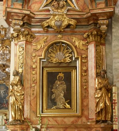 Zdjęcie nr 1: Retabulum architektoniczne, jednoosiowe, jednokondygnacyjne, ze zwieńczeniem,  posadowione na wysokim cokole. Nastawa ujęta ukośnie ustawionymi połówkami filarów na tle pilastrów, o kapitelach kompozytowych, podtrzymujących wydatne, przełamujące się nad nimi belkowanie z impostami i zwróconymi ku przodowi naczółkami, na których uskrzydlone, nagie putta, przepasane tkaninami. Zwieńczenie o lekko wklęsłych bokach zakończone gzymsem w formie łuku nadwieszonego. W partii fryzu kartusz ujęty wolutami, z lambrekinem u dołu, z muszlą palmetową u góry. W zwieńczeniu Oko Opatrzności na tle obłoków i promienistej glorii oraz dwie uskrzydlone główki anielskie. Dekorację ornamentalną tworzą kratki regencyjne, kampanule i muszle palmetowe. W części środkowej, we wnęce prostokątnej zamkniętej łukiem nadwieszonym półkolistym, w profilowanym obramieniu obraz Św. Katarzyna w profilowanej, prostokątnej ramie, nad nią rozłożysta palmeta. Wnęka ujęta kampanulami i gałązkami palmowymi. Po bokach nastawy dwie niezidentyfikowane postacie mężczyzn, całopostaciowe, w długich, silnie drapowanych sukniach, o wyrazistych twarzach, z krótkim zarostem i lekko falującymi włosami. Polichromia imitująca marmoryzację w odcieniach jasnych brązów, czerwieni i zieleni, figury o naturalnych karnacjach, złocenia szat figur i ornamentów, srebrzenia drobnych detali ornamentalnych.      
     
