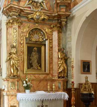 Zdjęcie nr 2: Retabulum architektoniczne, jednoosiowe, jednokondygnacyjne, ze zwieńczeniem,  posadowione na wysokim cokole. Nastawa ujęta ukośnie ustawionymi połówkami filarów na tle pilastrów, o kapitelach kompozytowych, podtrzymujących wydatne, przełamujące się nad nimi belkowanie z impostami i zwróconymi ku przodowi naczółkami, na których uskrzydlone, nagie putta, przepasane tkaninami. Zwieńczenie o lekko wklęsłych bokach zakończone gzymsem w formie łuku nadwieszonego. W partii fryzu kartusz ujęty wolutami, z lambrekinem u dołu, z muszlą palmetową u góry. W zwieńczeniu Oko Opatrzności na tle obłoków i promienistej glorii oraz dwie uskrzydlone główki anielskie. Dekorację ornamentalną tworzą kratki regencyjne, kampanule i muszle palmetowe. W części środkowej, we wnęce prostokątnej zamkniętej łukiem nadwieszonym półkolistym, w profilowanym obramieniu obraz Św. Katarzyna w profilowanej, prostokątnej ramie, nad nią rozłożysta palmeta. Wnęka ujęta kampanulami i gałązkami palmowymi. Po bokach nastawy dwie niezidentyfikowane postacie mężczyzn, całopostaciowe, w długich, silnie drapowanych sukniach, o wyrazistych twarzach, z krótkim zarostem i lekko falującymi włosami. Polichromia imitująca marmoryzację w odcieniach jasnych brązów, czerwieni i zieleni, figury o naturalnych karnacjach, złocenia szat figur i ornamentów, srebrzenia drobnych detali ornamentalnych.      
     
