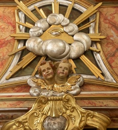 Zdjęcie nr 15: Retabulum architektoniczne, jednoosiowe, jednokondygnacyjne, ze zwieńczeniem,  posadowione na wysokim cokole. Nastawa ujęta ukośnie ustawionymi połówkami filarów na tle pilastrów, o kapitelach kompozytowych, podtrzymujących wydatne, przełamujące się nad nimi belkowanie z impostami i zwróconymi ku przodowi naczółkami, na których uskrzydlone, nagie putta, przepasane tkaninami. Zwieńczenie o lekko wklęsłych bokach zakończone gzymsem w formie łuku nadwieszonego. W partii fryzu kartusz ujęty wolutami, z lambrekinem u dołu, z muszlą palmetową u góry. W zwieńczeniu Oko Opatrzności na tle obłoków i promienistej glorii oraz dwie uskrzydlone główki anielskie. Dekorację ornamentalną tworzą kratki regencyjne, kampanule i muszle palmetowe. W części środkowej, we wnęce prostokątnej zamkniętej łukiem nadwieszonym półkolistym, w profilowanym obramieniu obraz Św. Katarzyna w profilowanej, prostokątnej ramie, nad nią rozłożysta palmeta. Wnęka ujęta kampanulami i gałązkami palmowymi. Po bokach nastawy dwie niezidentyfikowane postacie mężczyzn, całopostaciowe, w długich, silnie drapowanych sukniach, o wyrazistych twarzach, z krótkim zarostem i lekko falującymi włosami. Polichromia imitująca marmoryzację w odcieniach jasnych brązów, czerwieni i zieleni, figury o naturalnych karnacjach, złocenia szat figur i ornamentów, srebrzenia drobnych detali ornamentalnych.      
     
