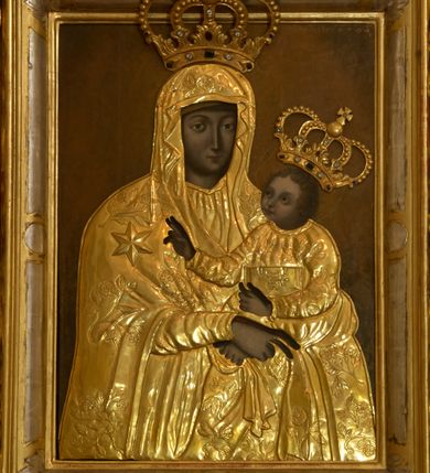 Zdjęcie nr 3: Retabulum architektoniczne, jednoosiowe, jednokondygnacyjne, ze zwieńczeniem, wzniesione na wysokim cokole. Nastawa ujęta ukośnie ustawionymi połówkami filarów na tle pilastrów, o kapitelach kompozytowych, podtrzymujących wydatne, przełamujące się nad nimi belkowanie z impostami i zwróconymi ku przodowi naczółkami, na których siedzą uskrzydlone, nagie putta, przepasane tkaninami. Zwieńczenie o lekko wklęsłych bokach zakończone gzymsem w formie łuku nadwieszonego. W partii fryzu kartusz ujęty wolutami, z lambrekinem u dołu z muszlą palmetową u góry. W zwieńczeniu gołębica Ducha Świętego na tle obłoków i promienistej glorii. Dekorację ornamentalną tworzą kratki regencyjne, kampanule i muszle palmetowe. W części środkowej obraz Matki Boskiej z Dzieciątkiem w typie Matki Boskiej Śnieżnej w drewnianej, złoconej sukience z koronami na głowie. Obraz z profilowanej ramie, złoconej i srebrzonej, ujętej po bokach zwisami z liści i kwiatów. Ponad obrazem rozłożysta muszla palmetowa. Po bokach nastawy dwie niezidentyfikowane postacie mężczyzn, całopostaciowe, w długich sukniach, z płaszczami zarzuconymi na ramiona, jedna z otwartą księgą w prawej dłoni, druga z rękoma złożonymi w geście modlitwy. Polichromia imitująca marmoryzację w odcieniach jasnych brązów, czerwieni i zieleni, figury o naturalnych karnacjach, złocenia szat figur i ornamentów, srebrzenia drobnych detali ornamentalnych.      


