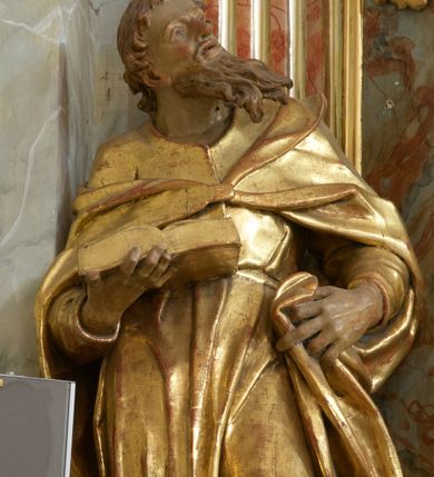 Zdjęcie nr 14: Retabulum architektoniczne, jednoosiowe, jednokondygnacyjne, ze zwieńczeniem, wzniesione na wysokim cokole. Nastawa ujęta ukośnie ustawionymi połówkami filarów na tle pilastrów, o kapitelach kompozytowych, podtrzymujących wydatne, przełamujące się nad nimi belkowanie z impostami i zwróconymi ku przodowi naczółkami, na których siedzą uskrzydlone, nagie putta, przepasane tkaninami. Zwieńczenie o lekko wklęsłych bokach zakończone gzymsem w formie łuku nadwieszonego. W partii fryzu kartusz ujęty wolutami, z lambrekinem u dołu z muszlą palmetową u góry. W zwieńczeniu gołębica Ducha Świętego na tle obłoków i promienistej glorii. Dekorację ornamentalną tworzą kratki regencyjne, kampanule i muszle palmetowe. W części środkowej obraz Matki Boskiej z Dzieciątkiem w typie Matki Boskiej Śnieżnej w drewnianej, złoconej sukience z koronami na głowie. Obraz z profilowanej ramie, złoconej i srebrzonej, ujętej po bokach zwisami z liści i kwiatów. Ponad obrazem rozłożysta muszla palmetowa. Po bokach nastawy dwie niezidentyfikowane postacie mężczyzn, całopostaciowe, w długich sukniach, z płaszczami zarzuconymi na ramiona, jedna z otwartą księgą w prawej dłoni, druga z rękoma złożonymi w geście modlitwy. Polichromia imitująca marmoryzację w odcieniach jasnych brązów, czerwieni i zieleni, figury o naturalnych karnacjach, złocenia szat figur i ornamentów, srebrzenia drobnych detali ornamentalnych.      


