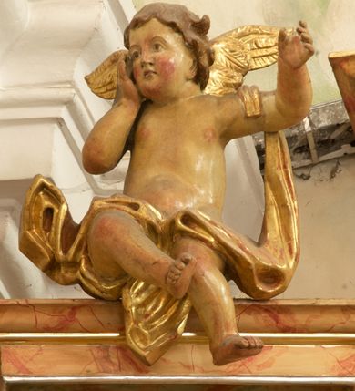 Zdjęcie nr 17: Retabulum architektoniczne, jednoosiowe, jednokondygnacyjne, ze zwieńczeniem, wzniesione na wysokim cokole. Nastawa ujęta ukośnie ustawionymi połówkami filarów na tle pilastrów, o kapitelach kompozytowych, podtrzymujących wydatne, przełamujące się nad nimi belkowanie z impostami i zwróconymi ku przodowi naczółkami, na których siedzą uskrzydlone, nagie putta, przepasane tkaninami. Zwieńczenie o lekko wklęsłych bokach zakończone gzymsem w formie łuku nadwieszonego. W partii fryzu kartusz ujęty wolutami, z lambrekinem u dołu z muszlą palmetową u góry. W zwieńczeniu gołębica Ducha Świętego na tle obłoków i promienistej glorii. Dekorację ornamentalną tworzą kratki regencyjne, kampanule i muszle palmetowe. W części środkowej obraz Matki Boskiej z Dzieciątkiem w typie Matki Boskiej Śnieżnej w drewnianej, złoconej sukience z koronami na głowie. Obraz z profilowanej ramie, złoconej i srebrzonej, ujętej po bokach zwisami z liści i kwiatów. Ponad obrazem rozłożysta muszla palmetowa. Po bokach nastawy dwie niezidentyfikowane postacie mężczyzn, całopostaciowe, w długich sukniach, z płaszczami zarzuconymi na ramiona, jedna z otwartą księgą w prawej dłoni, druga z rękoma złożonymi w geście modlitwy. Polichromia imitująca marmoryzację w odcieniach jasnych brązów, czerwieni i zieleni, figury o naturalnych karnacjach, złocenia szat figur i ornamentów, srebrzenia drobnych detali ornamentalnych.      


