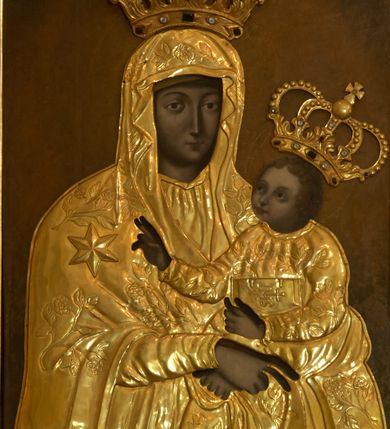 Zdjęcie nr 1: Obraz w kształcie stojącego prostokąta z przedstawieniem Matki Boskiej z Dzieciątkiem w typie Matki Boskiej Śnieżnej, umieszczony w bocznym ołtarzu usytuowanym po północnej stronie nawy głównej. Madonna została przedstawiona frontalnie, w półpostaci, z Dzieciątkiem Jezus na lewym ręku. W tej samej ręce trzyma chustkę, prawą składa w geście błogosławieństwa. Ma podłużną twarz z wąskim nosem, drobnymi ustami i dużymi, wyraźnie zaznaczonymi oczami. Zwrócone w trzech czwartych w prawo Dzieciątko spogląda na Matkę, prawą rękę wyciąga przed siebie w geście błogosławieństwa, lewą przytrzymuję zamkniętą księgę. Ma okrągłą, delikatną twarz z wąskim nosem, małymi ustami i okrągłymi oczami otoczoną puklami jasnych włosów. Szaty Matki Boskiej oraz Dzieciątka w formie rzeźbionej, złoconej sukienki z XVIII wieku, zdobionej ornamentem roślinno-kwiatowym. Na wysokości prawego ramienia Marii wypukła, sześcioramienna gwiazda. Obie postacie przedstawiono w zamkniętych koronach na głowach, które są wycięte z blachy, zdobione kamieniami jubilerskimi oraz aplikowanie na powierzchnię płótna i częściowo ramy. Tło w kolorze ciemnobrunatnym, za głowami na rozjaśnionym tle delikatnie zaznaczone nimby.
Rama prosta, profilowana, zdobiona po wewnętrznej stronie srebrzonymi płycinami oraz liśćmi w narożnikach. 
