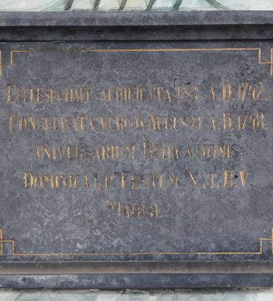 Zdjęcie nr 1: Kamienna tablica w kształcie leżącego prostokąta z kutą, złoconą inskrypcją „ECCLESIA HAEC AEDIFICATA EST A.D. 1742. / CONSECRATA VERO 6. AUGUSTI A.D. 1748. / ANIVERSARIUM DEDICATIONIS: / DOMINICA I. P. FESTUM NAT. B. V. / MARIAE” obwiedzioną cienką, złoconą linią przechodzącą w narożach w kwadraty. 