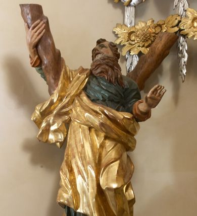 Zdjęcie nr 1: Święty został ukazany całopostaciowo, frontalnie, w kontrapoście, prawą ręką obejmuje belkę swojego krzyża. Jest ubrany w zieloną suknię sięgającą stóp i złoty płaszcz przerzucony przez prawe ramię i osłaniający do kolan korpus świętego. Głowę ma wzniesioną ku górze, okoloną długą, falującą brodą, z wydatnymi zakolami, otwartymi oczami i ustami. 