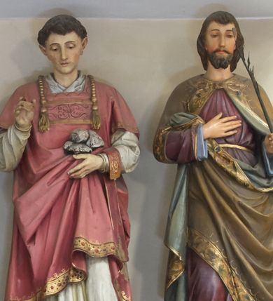 Zdjęcie nr 1: Figura pełna na cokole przedstawiająca św. Jana Chrzciciela. Święty stoi frontalnie, w lekkim kontrapoście, z lewą nogą wysuniętą do przodu; spogląda przed siebie, lekko w dół. Ma owalną twarz, małe oczy, wąski nos i niewielkie usta; twarz otacza ciemny zarost i ciemne, falowane włosy. Prawą ręką przytrzymuje kij, wokół którego owija się banderola z napisem „ECCE AGNUS DEI”, lewą wskazuje na leżącego obok jego prawej stopy niewielkiego baranka. Ubrany jest w przepasaną w pasie suknię ze skóry oraz czerwony, podbity niebieskim materiałem, spięty pod szyją płaszcz lamowany złotą taśmą zdobioną motywami roślinnymi. 
Na cokole napis „Ioannes Bapt(ista)”.
