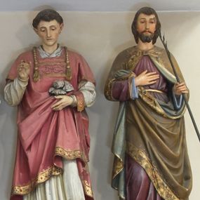 Zdjęcie nr 1: Figura pełna na cokole przedstawiająca św. Jana Chrzciciela. Święty stoi frontalnie, w lekkim kontrapoście, z lewą nogą wysuniętą do przodu; spogląda przed siebie, lekko w dół. Ma owalną twarz, małe oczy, wąski nos i niewielkie usta; twarz otacza ciemny zarost i ciemne, falowane włosy. Prawą ręką przytrzymuje kij, wokół którego owija się banderola z napisem „ECCE AGNUS DEI”, lewą wskazuje na leżącego obok jego prawej stopy niewielkiego baranka. Ubrany jest w przepasaną w pasie suknię ze skóry oraz czerwony, podbity niebieskim materiałem, spięty pod szyją płaszcz lamowany złotą taśmą zdobioną motywami roślinnymi. 
Na cokole napis „Ioannes Bapt(ista)”.
