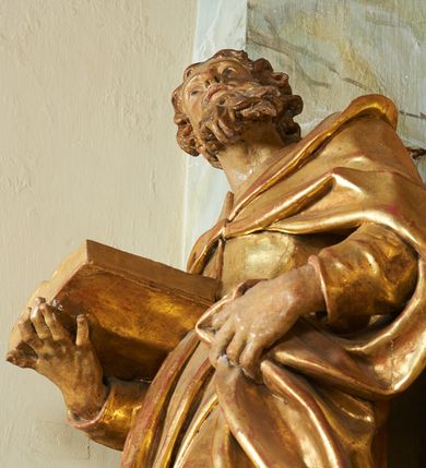 Zdjęcie nr 5: Figura ukazuje mężczyznę w całej postaci, w kontrapoście, ubranego w długą suknię przewiązaną w pasie i płaszcz spięty na piersiach, z otwartą księgą na prawej dłoni, z lewą przytrzymującą na biodrach płaszcz. Głowa zwrócona w lewo, ku górze, okolona długą, falującą brodą. 