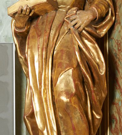 Zdjęcie nr 2: Figura ukazuje mężczyznę w całej postaci, w kontrapoście, ubranego w długą suknię przewiązaną w pasie i płaszcz spięty na piersiach, z otwartą księgą na prawej dłoni, z lewą przytrzymującą na biodrach płaszcz. Głowa zwrócona w lewo, ku górze, okolona długą, falującą brodą. 