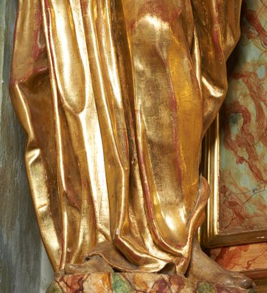 Zdjęcie nr 12: Figura ukazuje mężczyznę w całej postaci, w kontrapoście, ubranego w długą suknię przewiązaną w pasie i płaszcz spięty na piersiach, z otwartą księgą na prawej dłoni, z lewą przytrzymującą na biodrach płaszcz. Głowa zwrócona w lewo, ku górze, okolona długą, falującą brodą. 