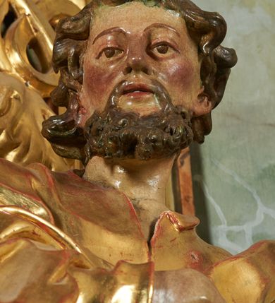 Zdjęcie nr 5: Rzeźba z ołtarza św. Katarzyny przedstawia świętego stojącego w lekkim wykroku z lewą nogą nieco wysuniętą do przodu. Głowa lekko pochylona, włosy kręcone, broda długa. Prawą rękę trzyma na piersi, lewa jest ugięta i uniesiona. Płaszcz i tunika bogato drapowane i złocone.