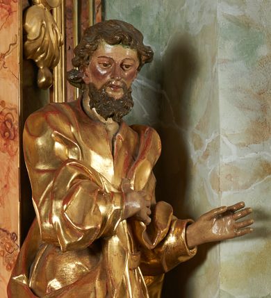 Zdjęcie nr 1: Rzeźba z ołtarza św. Katarzyny przedstawia świętego stojącego w lekkim wykroku z lewą nogą nieco wysuniętą do przodu. Głowa lekko pochylona, włosy kręcone, broda długa. Prawą rękę trzyma na piersi, lewa jest ugięta i uniesiona. Płaszcz i tunika bogato drapowane i złocone.