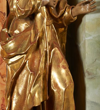 Zdjęcie nr 8: Rzeźba z ołtarza św. Katarzyny przedstawia świętego stojącego w lekkim wykroku z lewą nogą nieco wysuniętą do przodu. Głowa lekko pochylona, włosy kręcone, broda długa. Prawą rękę trzyma na piersi, lewa jest ugięta i uniesiona. Płaszcz i tunika bogato drapowane i złocone.