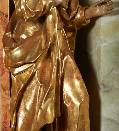 Zdjęcie nr 2: Rzeźba z ołtarza św. Katarzyny przedstawia świętego stojącego w lekkim wykroku z lewą nogą nieco wysuniętą do przodu. Głowa lekko pochylona, włosy kręcone, broda długa. Prawą rękę trzyma na piersi, lewa jest ugięta i uniesiona. Płaszcz i tunika bogato drapowane i złocone.