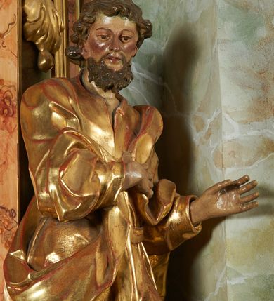 Zdjęcie nr 4: Rzeźba z ołtarza św. Katarzyny przedstawia świętego stojącego w lekkim wykroku z lewą nogą nieco wysuniętą do przodu. Głowa lekko pochylona, włosy kręcone, broda długa. Prawą rękę trzyma na piersi, lewa jest ugięta i uniesiona. Płaszcz i tunika bogato drapowane i złocone.