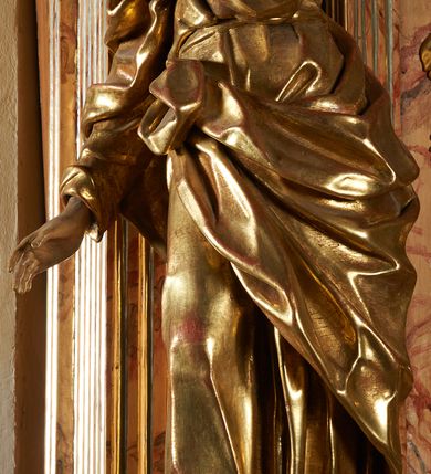 Zdjęcie nr 3: Rzeźba z ołtarza św. Katarzyny przedstawia świętego w lekkim wykroku z prawą nogą nieco wysuniętą do przodu. Wzrok zwrócony przed siebie, włosy długie, broda krótka. Lewa ręka jest położona na piersi, zaś prawa opuszczona i lekko odsunięta od ciała. Płaszcz i tunika bogato drapowane i złocone.