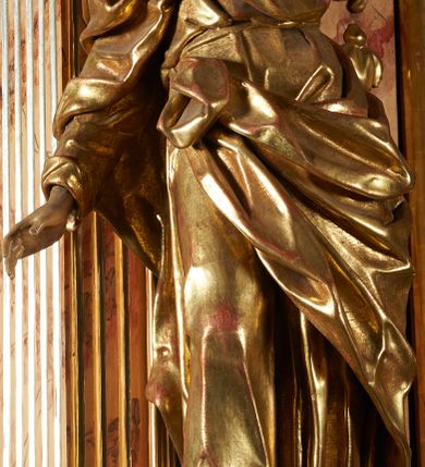 Zdjęcie nr 8: Rzeźba z ołtarza św. Katarzyny przedstawia świętego w lekkim wykroku z prawą nogą nieco wysuniętą do przodu. Wzrok zwrócony przed siebie, włosy długie, broda krótka. Lewa ręka jest położona na piersi, zaś prawa opuszczona i lekko odsunięta od ciała. Płaszcz i tunika bogato drapowane i złocone.