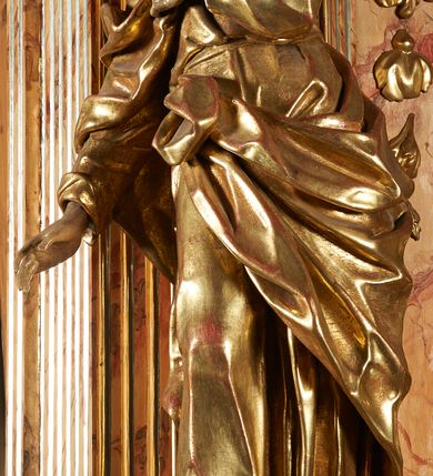 Zdjęcie nr 2: Rzeźba z ołtarza św. Katarzyny przedstawia świętego w lekkim wykroku z prawą nogą nieco wysuniętą do przodu. Wzrok zwrócony przed siebie, włosy długie, broda krótka. Lewa ręka jest położona na piersi, zaś prawa opuszczona i lekko odsunięta od ciała. Płaszcz i tunika bogato drapowane i złocone.