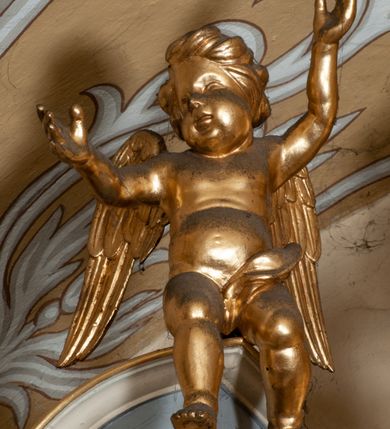 Zdjęcie nr 53: Ołtarz przyścienny, architektoniczny, jednokondygnacyjny ze zwieńczeniem, trójosiowy z bramkami. Mensa murowana prostopadłościenna, antepedium drewniane w złoconej ramie dekorowanej akantem. W jego polu medalion z monogramem maryjnym w glorii promienistej, otoczony przestylizowaną winoroślą. Tabernakulum w osi, metalowe, prostopadłościenne, jednodrzwiczkowe, z przedstawieniem kielicha z hostią. Retabulum ołtarzowe drewniane na cokole. Pole ołtarza z prostokątną, profilowaną ramą zamkniętą łukiem wklęsło-wypukłym z uskokiem. Mieści obraz Matki Boskiej Szkaplerznej, w bogatej akantowo-kwiatowej ramie z umieszczonym u góry, w osi owalnym obrazem Boga Ojca; zasuwany obrazami św. Józefa oraz św. Izydora Oracza. Pole jest ujęte ustawionymi na wysokich cokołach dekorowanych akantem, kolumnami o trzonach wypełnionych ornamentem roślinno-kwiatowym o układzie kandelabrowym oraz u podstawy z pełnoplastycznymi, uskrzydlonymi główkami aniołów; kapitele kompozytowe. Kolumny dźwigają niepełne, wyniesione pośrodku belkowanie, z odcinkami półkolistego przyczółka, na którym siedzą pełnoplastyczne, złocone figurki puttów. Fryz dekorowany akantem. W zwieńczeniu obraz św. Antoniego Padewskiego, prostokątny, zamknięty półkoliście, ujęty akantowymi wolutami. W bocznych osiach, ponad bramkami, prostokątne obrazy z lewej: św. Anny, z prawej: św. Joachima, dekorowane złoconym, ażurowym zwieńczeniem z kartuszy ujętych akantem. Ołtarz utrzymany w odcieniach beżu i szarości ze złoceniami w partiach ornamentów oraz w załamaniach profili architektonicznych.