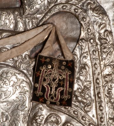 Zdjęcie nr 15: Ołtarz przyścienny, architektoniczny, jednokondygnacyjny ze zwieńczeniem, trójosiowy z bramkami. Mensa murowana prostopadłościenna, antepedium drewniane w złoconej ramie dekorowanej akantem. W jego polu medalion z monogramem maryjnym w glorii promienistej, otoczony przestylizowaną winoroślą. Tabernakulum w osi, metalowe, prostopadłościenne, jednodrzwiczkowe, z przedstawieniem kielicha z hostią. Retabulum ołtarzowe drewniane na cokole. Pole ołtarza z prostokątną, profilowaną ramą zamkniętą łukiem wklęsło-wypukłym z uskokiem. Mieści obraz Matki Boskiej Szkaplerznej, w bogatej akantowo-kwiatowej ramie z umieszczonym u góry, w osi owalnym obrazem Boga Ojca; zasuwany obrazami św. Józefa oraz św. Izydora Oracza. Pole jest ujęte ustawionymi na wysokich cokołach dekorowanych akantem, kolumnami o trzonach wypełnionych ornamentem roślinno-kwiatowym o układzie kandelabrowym oraz u podstawy z pełnoplastycznymi, uskrzydlonymi główkami aniołów; kapitele kompozytowe. Kolumny dźwigają niepełne, wyniesione pośrodku belkowanie, z odcinkami półkolistego przyczółka, na którym siedzą pełnoplastyczne, złocone figurki puttów. Fryz dekorowany akantem. W zwieńczeniu obraz św. Antoniego Padewskiego, prostokątny, zamknięty półkoliście, ujęty akantowymi wolutami. W bocznych osiach, ponad bramkami, prostokątne obrazy z lewej: św. Anny, z prawej: św. Joachima, dekorowane złoconym, ażurowym zwieńczeniem z kartuszy ujętych akantem. Ołtarz utrzymany w odcieniach beżu i szarości ze złoceniami w partiach ornamentów oraz w załamaniach profili architektonicznych.