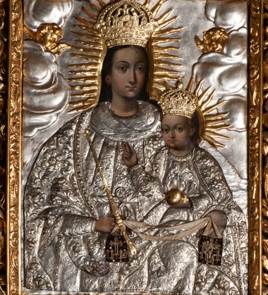 Zdjęcie nr 4: Ołtarz przyścienny, architektoniczny, jednokondygnacyjny ze zwieńczeniem, trójosiowy z bramkami. Mensa murowana prostopadłościenna, antepedium drewniane w złoconej ramie dekorowanej akantem. W jego polu medalion z monogramem maryjnym w glorii promienistej, otoczony przestylizowaną winoroślą. Tabernakulum w osi, metalowe, prostopadłościenne, jednodrzwiczkowe, z przedstawieniem kielicha z hostią. Retabulum ołtarzowe drewniane na cokole. Pole ołtarza z prostokątną, profilowaną ramą zamkniętą łukiem wklęsło-wypukłym z uskokiem. Mieści obraz Matki Boskiej Szkaplerznej, w bogatej akantowo-kwiatowej ramie z umieszczonym u góry, w osi owalnym obrazem Boga Ojca; zasuwany obrazami św. Józefa oraz św. Izydora Oracza. Pole jest ujęte ustawionymi na wysokich cokołach dekorowanych akantem, kolumnami o trzonach wypełnionych ornamentem roślinno-kwiatowym o układzie kandelabrowym oraz u podstawy z pełnoplastycznymi, uskrzydlonymi główkami aniołów; kapitele kompozytowe. Kolumny dźwigają niepełne, wyniesione pośrodku belkowanie, z odcinkami półkolistego przyczółka, na którym siedzą pełnoplastyczne, złocone figurki puttów. Fryz dekorowany akantem. W zwieńczeniu obraz św. Antoniego Padewskiego, prostokątny, zamknięty półkoliście, ujęty akantowymi wolutami. W bocznych osiach, ponad bramkami, prostokątne obrazy z lewej: św. Anny, z prawej: św. Joachima, dekorowane złoconym, ażurowym zwieńczeniem z kartuszy ujętych akantem. Ołtarz utrzymany w odcieniach beżu i szarości ze złoceniami w partiach ornamentów oraz w załamaniach profili architektonicznych.