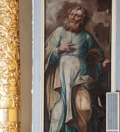 Zdjęcie nr 36: Ołtarz przyścienny, architektoniczny, jednokondygnacyjny ze zwieńczeniem, trójosiowy z bramkami. Mensa murowana prostopadłościenna, antepedium drewniane w złoconej ramie dekorowanej akantem. W jego polu medalion z monogramem maryjnym w glorii promienistej, otoczony przestylizowaną winoroślą. Tabernakulum w osi, metalowe, prostopadłościenne, jednodrzwiczkowe, z przedstawieniem kielicha z hostią. Retabulum ołtarzowe drewniane na cokole. Pole ołtarza z prostokątną, profilowaną ramą zamkniętą łukiem wklęsło-wypukłym z uskokiem. Mieści obraz Matki Boskiej Szkaplerznej, w bogatej akantowo-kwiatowej ramie z umieszczonym u góry, w osi owalnym obrazem Boga Ojca; zasuwany obrazami św. Józefa oraz św. Izydora Oracza. Pole jest ujęte ustawionymi na wysokich cokołach dekorowanych akantem, kolumnami o trzonach wypełnionych ornamentem roślinno-kwiatowym o układzie kandelabrowym oraz u podstawy z pełnoplastycznymi, uskrzydlonymi główkami aniołów; kapitele kompozytowe. Kolumny dźwigają niepełne, wyniesione pośrodku belkowanie, z odcinkami półkolistego przyczółka, na którym siedzą pełnoplastyczne, złocone figurki puttów. Fryz dekorowany akantem. W zwieńczeniu obraz św. Antoniego Padewskiego, prostokątny, zamknięty półkoliście, ujęty akantowymi wolutami. W bocznych osiach, ponad bramkami, prostokątne obrazy z lewej: św. Anny, z prawej: św. Joachima, dekorowane złoconym, ażurowym zwieńczeniem z kartuszy ujętych akantem. Ołtarz utrzymany w odcieniach beżu i szarości ze złoceniami w partiach ornamentów oraz w załamaniach profili architektonicznych.