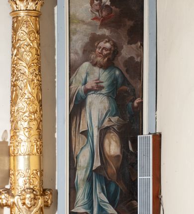 Zdjęcie nr 35: Ołtarz przyścienny, architektoniczny, jednokondygnacyjny ze zwieńczeniem, trójosiowy z bramkami. Mensa murowana prostopadłościenna, antepedium drewniane w złoconej ramie dekorowanej akantem. W jego polu medalion z monogramem maryjnym w glorii promienistej, otoczony przestylizowaną winoroślą. Tabernakulum w osi, metalowe, prostopadłościenne, jednodrzwiczkowe, z przedstawieniem kielicha z hostią. Retabulum ołtarzowe drewniane na cokole. Pole ołtarza z prostokątną, profilowaną ramą zamkniętą łukiem wklęsło-wypukłym z uskokiem. Mieści obraz Matki Boskiej Szkaplerznej, w bogatej akantowo-kwiatowej ramie z umieszczonym u góry, w osi owalnym obrazem Boga Ojca; zasuwany obrazami św. Józefa oraz św. Izydora Oracza. Pole jest ujęte ustawionymi na wysokich cokołach dekorowanych akantem, kolumnami o trzonach wypełnionych ornamentem roślinno-kwiatowym o układzie kandelabrowym oraz u podstawy z pełnoplastycznymi, uskrzydlonymi główkami aniołów; kapitele kompozytowe. Kolumny dźwigają niepełne, wyniesione pośrodku belkowanie, z odcinkami półkolistego przyczółka, na którym siedzą pełnoplastyczne, złocone figurki puttów. Fryz dekorowany akantem. W zwieńczeniu obraz św. Antoniego Padewskiego, prostokątny, zamknięty półkoliście, ujęty akantowymi wolutami. W bocznych osiach, ponad bramkami, prostokątne obrazy z lewej: św. Anny, z prawej: św. Joachima, dekorowane złoconym, ażurowym zwieńczeniem z kartuszy ujętych akantem. Ołtarz utrzymany w odcieniach beżu i szarości ze złoceniami w partiach ornamentów oraz w załamaniach profili architektonicznych.