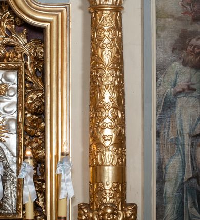 Zdjęcie nr 56: Ołtarz przyścienny, architektoniczny, jednokondygnacyjny ze zwieńczeniem, trójosiowy z bramkami. Mensa murowana prostopadłościenna, antepedium drewniane w złoconej ramie dekorowanej akantem. W jego polu medalion z monogramem maryjnym w glorii promienistej, otoczony przestylizowaną winoroślą. Tabernakulum w osi, metalowe, prostopadłościenne, jednodrzwiczkowe, z przedstawieniem kielicha z hostią. Retabulum ołtarzowe drewniane na cokole. Pole ołtarza z prostokątną, profilowaną ramą zamkniętą łukiem wklęsło-wypukłym z uskokiem. Mieści obraz Matki Boskiej Szkaplerznej, w bogatej akantowo-kwiatowej ramie z umieszczonym u góry, w osi owalnym obrazem Boga Ojca; zasuwany obrazami św. Józefa oraz św. Izydora Oracza. Pole jest ujęte ustawionymi na wysokich cokołach dekorowanych akantem, kolumnami o trzonach wypełnionych ornamentem roślinno-kwiatowym o układzie kandelabrowym oraz u podstawy z pełnoplastycznymi, uskrzydlonymi główkami aniołów; kapitele kompozytowe. Kolumny dźwigają niepełne, wyniesione pośrodku belkowanie, z odcinkami półkolistego przyczółka, na którym siedzą pełnoplastyczne, złocone figurki puttów. Fryz dekorowany akantem. W zwieńczeniu obraz św. Antoniego Padewskiego, prostokątny, zamknięty półkoliście, ujęty akantowymi wolutami. W bocznych osiach, ponad bramkami, prostokątne obrazy z lewej: św. Anny, z prawej: św. Joachima, dekorowane złoconym, ażurowym zwieńczeniem z kartuszy ujętych akantem. Ołtarz utrzymany w odcieniach beżu i szarości ze złoceniami w partiach ornamentów oraz w załamaniach profili architektonicznych.