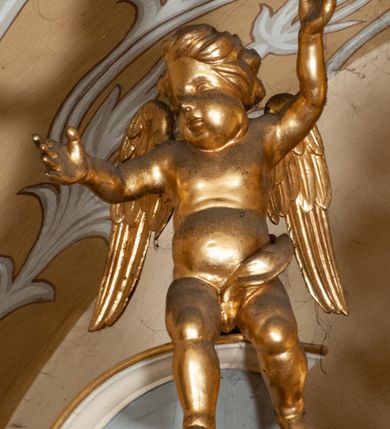 Zdjęcie nr 58: Ołtarz przyścienny, architektoniczny, jednokondygnacyjny ze zwieńczeniem, trójosiowy z bramkami. Mensa murowana prostopadłościenna, antepedium drewniane w złoconej ramie dekorowanej akantem. W jego polu medalion z monogramem maryjnym w glorii promienistej, otoczony przestylizowaną winoroślą. Tabernakulum w osi, metalowe, prostopadłościenne, jednodrzwiczkowe, z przedstawieniem kielicha z hostią. Retabulum ołtarzowe drewniane na cokole. Pole ołtarza z prostokątną, profilowaną ramą zamkniętą łukiem wklęsło-wypukłym z uskokiem. Mieści obraz Matki Boskiej Szkaplerznej, w bogatej akantowo-kwiatowej ramie z umieszczonym u góry, w osi owalnym obrazem Boga Ojca; zasuwany obrazami św. Józefa oraz św. Izydora Oracza. Pole jest ujęte ustawionymi na wysokich cokołach dekorowanych akantem, kolumnami o trzonach wypełnionych ornamentem roślinno-kwiatowym o układzie kandelabrowym oraz u podstawy z pełnoplastycznymi, uskrzydlonymi główkami aniołów; kapitele kompozytowe. Kolumny dźwigają niepełne, wyniesione pośrodku belkowanie, z odcinkami półkolistego przyczółka, na którym siedzą pełnoplastyczne, złocone figurki puttów. Fryz dekorowany akantem. W zwieńczeniu obraz św. Antoniego Padewskiego, prostokątny, zamknięty półkoliście, ujęty akantowymi wolutami. W bocznych osiach, ponad bramkami, prostokątne obrazy z lewej: św. Anny, z prawej: św. Joachima, dekorowane złoconym, ażurowym zwieńczeniem z kartuszy ujętych akantem. Ołtarz utrzymany w odcieniach beżu i szarości ze złoceniami w partiach ornamentów oraz w załamaniach profili architektonicznych.