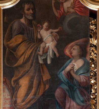 Zdjęcie nr 20: Ołtarz przyścienny, architektoniczny, jednokondygnacyjny ze zwieńczeniem, trójosiowy z bramkami. Mensa murowana prostopadłościenna, antepedium drewniane w złoconej ramie dekorowanej akantem. W jego polu medalion z monogramem maryjnym w glorii promienistej, otoczony przestylizowaną winoroślą. Tabernakulum w osi, metalowe, prostopadłościenne, jednodrzwiczkowe, z przedstawieniem kielicha z hostią. Retabulum ołtarzowe drewniane na cokole. Pole ołtarza z prostokątną, profilowaną ramą zamkniętą łukiem wklęsło-wypukłym z uskokiem. Mieści obraz Matki Boskiej Szkaplerznej, w bogatej akantowo-kwiatowej ramie z umieszczonym u góry, w osi owalnym obrazem Boga Ojca; zasuwany obrazami św. Józefa oraz św. Izydora Oracza. Pole jest ujęte ustawionymi na wysokich cokołach dekorowanych akantem, kolumnami o trzonach wypełnionych ornamentem roślinno-kwiatowym o układzie kandelabrowym oraz u podstawy z pełnoplastycznymi, uskrzydlonymi główkami aniołów; kapitele kompozytowe. Kolumny dźwigają niepełne, wyniesione pośrodku belkowanie, z odcinkami półkolistego przyczółka, na którym siedzą pełnoplastyczne, złocone figurki puttów. Fryz dekorowany akantem. W zwieńczeniu obraz św. Antoniego Padewskiego, prostokątny, zamknięty półkoliście, ujęty akantowymi wolutami. W bocznych osiach, ponad bramkami, prostokątne obrazy z lewej: św. Anny, z prawej: św. Joachima, dekorowane złoconym, ażurowym zwieńczeniem z kartuszy ujętych akantem. Ołtarz utrzymany w odcieniach beżu i szarości ze złoceniami w partiach ornamentów oraz w załamaniach profili architektonicznych.