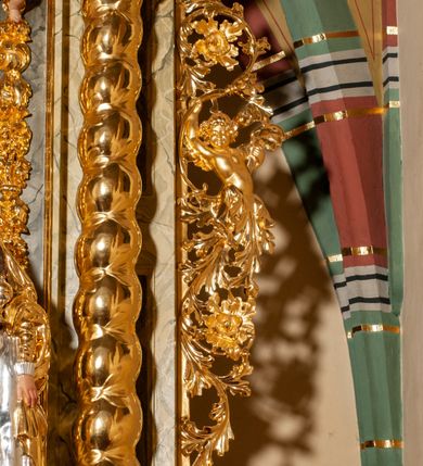 Zdjęcie nr 19: Drewniany, przyścienny ołtarz o formach architektonicznych, jednoosiowy, jednokondygnacyjny ze zwieńczeniem. Mensa murowana w kształcie prostopadłościanu zwieńczonego profilowanym gzymsem; antepedium prostokątne, w drewnianej, płaskorzeźbionej w motywy akantowe, złoconej ramie, dwustronne. Awers tłoczony, srebrzony, wykonany w technice papier mâché; rewers z malowanym na desce wyobrażeniem Veraicon na tle narzędzi męki. Tabernakulum na osi, złożone z mosiężnej, złoconej, sześciobocznej skrzynki w rozbudowanej, drewnianej obudowie o formach architektonicznych. Na nim tron wystawienia w kształcie niszy dekorowanej kratką, nakrytej kopułką z latarnią i przysłoniętej złapanymi po bokach kotarami. Na latarni rzeźbione przedstawienie pelikana karmiącego pisklęta własną krwią. Skrzynkę z tronem ulokowano na tle parawanu ustawionego na podwójnym cokole, ażurowego w górnej części, wypełnionego dekoracją roślinną, złączonego z kopułka spływami. 
Retabulum ołtarzowe drewniane wsparte na wysokim, dwudzielnym, murowanym cokole. Cokół w obudowie drewnianej, jego kondygnacje wydzielone wydatnymi, silnie występującymi przed lico gzymsami; mocno wysunięte ku przodowi części przednie. Ich lica z prostokątnymi płycinami mieszczącymi suchy akant; w części środkowej drugiej kondygnacji cokołu, dodatkowo pełnoplastyczne główki puttów. Na cokole ustawione zdwojone, złocone kolumny o skręconych trzonach i kompozytowych kapitelach. Pomiędzy nimi płyciny wypełnione dekoracją w formie podwieszonego wieńca, u jego szczytu putta pełniące rolę atlantów. Na tle płycin ustawione drewniane, złocone figury z lewej św. Zygmunta i z prawej św. Marii Magdaleny – patronów kościoła. Pole ołtarza z prostokątną niszą zamkniętą łukiem wyniesionym; ujętą płaskorzeźbioną, złoconą ramą zdobioną suchym akantem. W niszy pełnoplastyczny, polichromowany i złocony krucyfiks na aksamitnym tle, flankowany przez płaskorzeźbione wyobrażenia słońca i księżyca. Nisza zasuwana obrazem z Przemienieniem na górze Tabor, w drewnianej, złoconej sukience. Kolumny dźwigają pełne, wyłamane na osiach podpór belkowanie, z wydatnym, silnie profilowanym gzymsem; na jego osi złocony monogram „IHS” w otoku ze srebrzonych obłoków na tle promienistej glorii. Całość wieńczą fragmenty przerwanego przyczółka o formach wklęsło-wypukłych, z ażurową dekoracją z suchego akantu. Pomiędzy ramionami przyczółka złocona gloria promienista, w centrum której płaskorzeźbiona postać Boga Ojca siedzącego na srebrzonym obłoku ze srebrzoną gołębicą Ducha Świętego u stóp. Na ramionach glorii uskrzydlone główki puttów, niektóre na tle obłoków. Po bokach, na gzymsie siedzące postaci nagich, adorujących puttów. Ołtarz ujęty ażurowymi, złoconymi uszami z suchego akantu, w który wplecione są groteskowe putta trzymające pochodnie. Większość powierzchni ołtarza marmoryzowana, w kolorze jasnej, oliwkowej zieleni, z ciemniejszymi brązowymi elementami wypełniającymi płyciny. Złocenia w partiach ornamentów, kolumn oraz załamaniach profili elementów architektonicznych; srebrzone obłoki, części szat postaci i pelikan. 