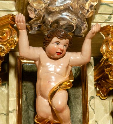 Zdjęcie nr 28: Drewniany, przyścienny ołtarz o formach architektonicznych, jednoosiowy, jednokondygnacyjny ze zwieńczeniem. Mensa murowana w kształcie prostopadłościanu zwieńczonego profilowanym gzymsem; antepedium prostokątne, w drewnianej, płaskorzeźbionej w motywy akantowe, złoconej ramie, dwustronne. Awers tłoczony, srebrzony, wykonany w technice papier mâché; rewers z malowanym na desce wyobrażeniem Veraicon na tle narzędzi męki. Tabernakulum na osi, złożone z mosiężnej, złoconej, sześciobocznej skrzynki w rozbudowanej, drewnianej obudowie o formach architektonicznych. Na nim tron wystawienia w kształcie niszy dekorowanej kratką, nakrytej kopułką z latarnią i przysłoniętej złapanymi po bokach kotarami. Na latarni rzeźbione przedstawienie pelikana karmiącego pisklęta własną krwią. Skrzynkę z tronem ulokowano na tle parawanu ustawionego na podwójnym cokole, ażurowego w górnej części, wypełnionego dekoracją roślinną, złączonego z kopułka spływami. 
Retabulum ołtarzowe drewniane wsparte na wysokim, dwudzielnym, murowanym cokole. Cokół w obudowie drewnianej, jego kondygnacje wydzielone wydatnymi, silnie występującymi przed lico gzymsami; mocno wysunięte ku przodowi części przednie. Ich lica z prostokątnymi płycinami mieszczącymi suchy akant; w części środkowej drugiej kondygnacji cokołu, dodatkowo pełnoplastyczne główki puttów. Na cokole ustawione zdwojone, złocone kolumny o skręconych trzonach i kompozytowych kapitelach. Pomiędzy nimi płyciny wypełnione dekoracją w formie podwieszonego wieńca, u jego szczytu putta pełniące rolę atlantów. Na tle płycin ustawione drewniane, złocone figury z lewej św. Zygmunta i z prawej św. Marii Magdaleny – patronów kościoła. Pole ołtarza z prostokątną niszą zamkniętą łukiem wyniesionym; ujętą płaskorzeźbioną, złoconą ramą zdobioną suchym akantem. W niszy pełnoplastyczny, polichromowany i złocony krucyfiks na aksamitnym tle, flankowany przez płaskorzeźbione wyobrażenia słońca i księżyca. Nisza zasuwana obrazem z Przemienieniem na górze Tabor, w drewnianej, złoconej sukience. Kolumny dźwigają pełne, wyłamane na osiach podpór belkowanie, z wydatnym, silnie profilowanym gzymsem; na jego osi złocony monogram „IHS” w otoku ze srebrzonych obłoków na tle promienistej glorii. Całość wieńczą fragmenty przerwanego przyczółka o formach wklęsło-wypukłych, z ażurową dekoracją z suchego akantu. Pomiędzy ramionami przyczółka złocona gloria promienista, w centrum której płaskorzeźbiona postać Boga Ojca siedzącego na srebrzonym obłoku ze srebrzoną gołębicą Ducha Świętego u stóp. Na ramionach glorii uskrzydlone główki puttów, niektóre na tle obłoków. Po bokach, na gzymsie siedzące postaci nagich, adorujących puttów. Ołtarz ujęty ażurowymi, złoconymi uszami z suchego akantu, w który wplecione są groteskowe putta trzymające pochodnie. Większość powierzchni ołtarza marmoryzowana, w kolorze jasnej, oliwkowej zieleni, z ciemniejszymi brązowymi elementami wypełniającymi płyciny. Złocenia w partiach ornamentów, kolumn oraz załamaniach profili elementów architektonicznych; srebrzone obłoki, części szat postaci i pelikan. 