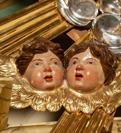 Zdjęcie nr 38: Drewniany, przyścienny ołtarz o formach architektonicznych, jednoosiowy, jednokondygnacyjny ze zwieńczeniem. Mensa murowana w kształcie prostopadłościanu zwieńczonego profilowanym gzymsem; antepedium prostokątne, w drewnianej, płaskorzeźbionej w motywy akantowe, złoconej ramie, dwustronne. Awers tłoczony, srebrzony, wykonany w technice papier mâché; rewers z malowanym na desce wyobrażeniem Veraicon na tle narzędzi męki. Tabernakulum na osi, złożone z mosiężnej, złoconej, sześciobocznej skrzynki w rozbudowanej, drewnianej obudowie o formach architektonicznych. Na nim tron wystawienia w kształcie niszy dekorowanej kratką, nakrytej kopułką z latarnią i przysłoniętej złapanymi po bokach kotarami. Na latarni rzeźbione przedstawienie pelikana karmiącego pisklęta własną krwią. Skrzynkę z tronem ulokowano na tle parawanu ustawionego na podwójnym cokole, ażurowego w górnej części, wypełnionego dekoracją roślinną, złączonego z kopułka spływami. 
Retabulum ołtarzowe drewniane wsparte na wysokim, dwudzielnym, murowanym cokole. Cokół w obudowie drewnianej, jego kondygnacje wydzielone wydatnymi, silnie występującymi przed lico gzymsami; mocno wysunięte ku przodowi części przednie. Ich lica z prostokątnymi płycinami mieszczącymi suchy akant; w części środkowej drugiej kondygnacji cokołu, dodatkowo pełnoplastyczne główki puttów. Na cokole ustawione zdwojone, złocone kolumny o skręconych trzonach i kompozytowych kapitelach. Pomiędzy nimi płyciny wypełnione dekoracją w formie podwieszonego wieńca, u jego szczytu putta pełniące rolę atlantów. Na tle płycin ustawione drewniane, złocone figury z lewej św. Zygmunta i z prawej św. Marii Magdaleny – patronów kościoła. Pole ołtarza z prostokątną niszą zamkniętą łukiem wyniesionym; ujętą płaskorzeźbioną, złoconą ramą zdobioną suchym akantem. W niszy pełnoplastyczny, polichromowany i złocony krucyfiks na aksamitnym tle, flankowany przez płaskorzeźbione wyobrażenia słońca i księżyca. Nisza zasuwana obrazem z Przemienieniem na górze Tabor, w drewnianej, złoconej sukience. Kolumny dźwigają pełne, wyłamane na osiach podpór belkowanie, z wydatnym, silnie profilowanym gzymsem; na jego osi złocony monogram „IHS” w otoku ze srebrzonych obłoków na tle promienistej glorii. Całość wieńczą fragmenty przerwanego przyczółka o formach wklęsło-wypukłych, z ażurową dekoracją z suchego akantu. Pomiędzy ramionami przyczółka złocona gloria promienista, w centrum której płaskorzeźbiona postać Boga Ojca siedzącego na srebrzonym obłoku ze srebrzoną gołębicą Ducha Świętego u stóp. Na ramionach glorii uskrzydlone główki puttów, niektóre na tle obłoków. Po bokach, na gzymsie siedzące postaci nagich, adorujących puttów. Ołtarz ujęty ażurowymi, złoconymi uszami z suchego akantu, w który wplecione są groteskowe putta trzymające pochodnie. Większość powierzchni ołtarza marmoryzowana, w kolorze jasnej, oliwkowej zieleni, z ciemniejszymi brązowymi elementami wypełniającymi płyciny. Złocenia w partiach ornamentów, kolumn oraz załamaniach profili elementów architektonicznych; srebrzone obłoki, części szat postaci i pelikan. 