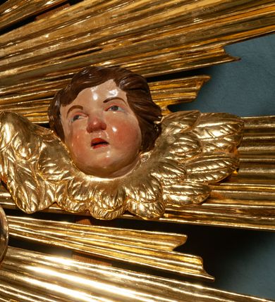 Zdjęcie nr 44: Drewniany, przyścienny ołtarz o formach architektonicznych, jednoosiowy, jednokondygnacyjny ze zwieńczeniem. Mensa murowana w kształcie prostopadłościanu zwieńczonego profilowanym gzymsem; antepedium prostokątne, w drewnianej, płaskorzeźbionej w motywy akantowe, złoconej ramie, dwustronne. Awers tłoczony, srebrzony, wykonany w technice papier mâché; rewers z malowanym na desce wyobrażeniem Veraicon na tle narzędzi męki. Tabernakulum na osi, złożone z mosiężnej, złoconej, sześciobocznej skrzynki w rozbudowanej, drewnianej obudowie o formach architektonicznych. Na nim tron wystawienia w kształcie niszy dekorowanej kratką, nakrytej kopułką z latarnią i przysłoniętej złapanymi po bokach kotarami. Na latarni rzeźbione przedstawienie pelikana karmiącego pisklęta własną krwią. Skrzynkę z tronem ulokowano na tle parawanu ustawionego na podwójnym cokole, ażurowego w górnej części, wypełnionego dekoracją roślinną, złączonego z kopułka spływami. 
Retabulum ołtarzowe drewniane wsparte na wysokim, dwudzielnym, murowanym cokole. Cokół w obudowie drewnianej, jego kondygnacje wydzielone wydatnymi, silnie występującymi przed lico gzymsami; mocno wysunięte ku przodowi części przednie. Ich lica z prostokątnymi płycinami mieszczącymi suchy akant; w części środkowej drugiej kondygnacji cokołu, dodatkowo pełnoplastyczne główki puttów. Na cokole ustawione zdwojone, złocone kolumny o skręconych trzonach i kompozytowych kapitelach. Pomiędzy nimi płyciny wypełnione dekoracją w formie podwieszonego wieńca, u jego szczytu putta pełniące rolę atlantów. Na tle płycin ustawione drewniane, złocone figury z lewej św. Zygmunta i z prawej św. Marii Magdaleny – patronów kościoła. Pole ołtarza z prostokątną niszą zamkniętą łukiem wyniesionym; ujętą płaskorzeźbioną, złoconą ramą zdobioną suchym akantem. W niszy pełnoplastyczny, polichromowany i złocony krucyfiks na aksamitnym tle, flankowany przez płaskorzeźbione wyobrażenia słońca i księżyca. Nisza zasuwana obrazem z Przemienieniem na górze Tabor, w drewnianej, złoconej sukience. Kolumny dźwigają pełne, wyłamane na osiach podpór belkowanie, z wydatnym, silnie profilowanym gzymsem; na jego osi złocony monogram „IHS” w otoku ze srebrzonych obłoków na tle promienistej glorii. Całość wieńczą fragmenty przerwanego przyczółka o formach wklęsło-wypukłych, z ażurową dekoracją z suchego akantu. Pomiędzy ramionami przyczółka złocona gloria promienista, w centrum której płaskorzeźbiona postać Boga Ojca siedzącego na srebrzonym obłoku ze srebrzoną gołębicą Ducha Świętego u stóp. Na ramionach glorii uskrzydlone główki puttów, niektóre na tle obłoków. Po bokach, na gzymsie siedzące postaci nagich, adorujących puttów. Ołtarz ujęty ażurowymi, złoconymi uszami z suchego akantu, w który wplecione są groteskowe putta trzymające pochodnie. Większość powierzchni ołtarza marmoryzowana, w kolorze jasnej, oliwkowej zieleni, z ciemniejszymi brązowymi elementami wypełniającymi płyciny. Złocenia w partiach ornamentów, kolumn oraz załamaniach profili elementów architektonicznych; srebrzone obłoki, części szat postaci i pelikan. 