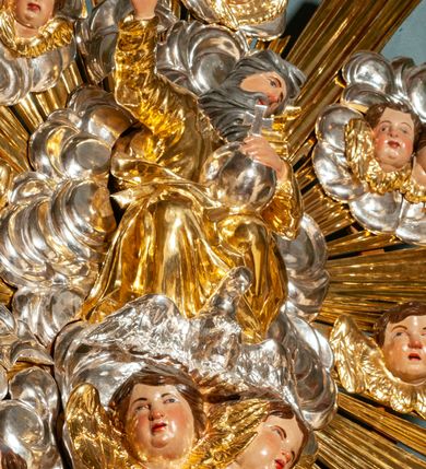 Zdjęcie nr 47: Drewniany, przyścienny ołtarz o formach architektonicznych, jednoosiowy, jednokondygnacyjny ze zwieńczeniem. Mensa murowana w kształcie prostopadłościanu zwieńczonego profilowanym gzymsem; antepedium prostokątne, w drewnianej, płaskorzeźbionej w motywy akantowe, złoconej ramie, dwustronne. Awers tłoczony, srebrzony, wykonany w technice papier mâché; rewers z malowanym na desce wyobrażeniem Veraicon na tle narzędzi męki. Tabernakulum na osi, złożone z mosiężnej, złoconej, sześciobocznej skrzynki w rozbudowanej, drewnianej obudowie o formach architektonicznych. Na nim tron wystawienia w kształcie niszy dekorowanej kratką, nakrytej kopułką z latarnią i przysłoniętej złapanymi po bokach kotarami. Na latarni rzeźbione przedstawienie pelikana karmiącego pisklęta własną krwią. Skrzynkę z tronem ulokowano na tle parawanu ustawionego na podwójnym cokole, ażurowego w górnej części, wypełnionego dekoracją roślinną, złączonego z kopułka spływami. 
Retabulum ołtarzowe drewniane wsparte na wysokim, dwudzielnym, murowanym cokole. Cokół w obudowie drewnianej, jego kondygnacje wydzielone wydatnymi, silnie występującymi przed lico gzymsami; mocno wysunięte ku przodowi części przednie. Ich lica z prostokątnymi płycinami mieszczącymi suchy akant; w części środkowej drugiej kondygnacji cokołu, dodatkowo pełnoplastyczne główki puttów. Na cokole ustawione zdwojone, złocone kolumny o skręconych trzonach i kompozytowych kapitelach. Pomiędzy nimi płyciny wypełnione dekoracją w formie podwieszonego wieńca, u jego szczytu putta pełniące rolę atlantów. Na tle płycin ustawione drewniane, złocone figury z lewej św. Zygmunta i z prawej św. Marii Magdaleny – patronów kościoła. Pole ołtarza z prostokątną niszą zamkniętą łukiem wyniesionym; ujętą płaskorzeźbioną, złoconą ramą zdobioną suchym akantem. W niszy pełnoplastyczny, polichromowany i złocony krucyfiks na aksamitnym tle, flankowany przez płaskorzeźbione wyobrażenia słońca i księżyca. Nisza zasuwana obrazem z Przemienieniem na górze Tabor, w drewnianej, złoconej sukience. Kolumny dźwigają pełne, wyłamane na osiach podpór belkowanie, z wydatnym, silnie profilowanym gzymsem; na jego osi złocony monogram „IHS” w otoku ze srebrzonych obłoków na tle promienistej glorii. Całość wieńczą fragmenty przerwanego przyczółka o formach wklęsło-wypukłych, z ażurową dekoracją z suchego akantu. Pomiędzy ramionami przyczółka złocona gloria promienista, w centrum której płaskorzeźbiona postać Boga Ojca siedzącego na srebrzonym obłoku ze srebrzoną gołębicą Ducha Świętego u stóp. Na ramionach glorii uskrzydlone główki puttów, niektóre na tle obłoków. Po bokach, na gzymsie siedzące postaci nagich, adorujących puttów. Ołtarz ujęty ażurowymi, złoconymi uszami z suchego akantu, w który wplecione są groteskowe putta trzymające pochodnie. Większość powierzchni ołtarza marmoryzowana, w kolorze jasnej, oliwkowej zieleni, z ciemniejszymi brązowymi elementami wypełniającymi płyciny. Złocenia w partiach ornamentów, kolumn oraz załamaniach profili elementów architektonicznych; srebrzone obłoki, części szat postaci i pelikan. 