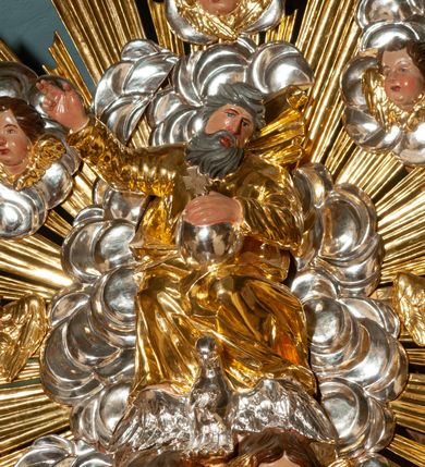 Zdjęcie nr 48: Drewniany, przyścienny ołtarz o formach architektonicznych, jednoosiowy, jednokondygnacyjny ze zwieńczeniem. Mensa murowana w kształcie prostopadłościanu zwieńczonego profilowanym gzymsem; antepedium prostokątne, w drewnianej, płaskorzeźbionej w motywy akantowe, złoconej ramie, dwustronne. Awers tłoczony, srebrzony, wykonany w technice papier mâché; rewers z malowanym na desce wyobrażeniem Veraicon na tle narzędzi męki. Tabernakulum na osi, złożone z mosiężnej, złoconej, sześciobocznej skrzynki w rozbudowanej, drewnianej obudowie o formach architektonicznych. Na nim tron wystawienia w kształcie niszy dekorowanej kratką, nakrytej kopułką z latarnią i przysłoniętej złapanymi po bokach kotarami. Na latarni rzeźbione przedstawienie pelikana karmiącego pisklęta własną krwią. Skrzynkę z tronem ulokowano na tle parawanu ustawionego na podwójnym cokole, ażurowego w górnej części, wypełnionego dekoracją roślinną, złączonego z kopułka spływami. 
Retabulum ołtarzowe drewniane wsparte na wysokim, dwudzielnym, murowanym cokole. Cokół w obudowie drewnianej, jego kondygnacje wydzielone wydatnymi, silnie występującymi przed lico gzymsami; mocno wysunięte ku przodowi części przednie. Ich lica z prostokątnymi płycinami mieszczącymi suchy akant; w części środkowej drugiej kondygnacji cokołu, dodatkowo pełnoplastyczne główki puttów. Na cokole ustawione zdwojone, złocone kolumny o skręconych trzonach i kompozytowych kapitelach. Pomiędzy nimi płyciny wypełnione dekoracją w formie podwieszonego wieńca, u jego szczytu putta pełniące rolę atlantów. Na tle płycin ustawione drewniane, złocone figury z lewej św. Zygmunta i z prawej św. Marii Magdaleny – patronów kościoła. Pole ołtarza z prostokątną niszą zamkniętą łukiem wyniesionym; ujętą płaskorzeźbioną, złoconą ramą zdobioną suchym akantem. W niszy pełnoplastyczny, polichromowany i złocony krucyfiks na aksamitnym tle, flankowany przez płaskorzeźbione wyobrażenia słońca i księżyca. Nisza zasuwana obrazem z Przemienieniem na górze Tabor, w drewnianej, złoconej sukience. Kolumny dźwigają pełne, wyłamane na osiach podpór belkowanie, z wydatnym, silnie profilowanym gzymsem; na jego osi złocony monogram „IHS” w otoku ze srebrzonych obłoków na tle promienistej glorii. Całość wieńczą fragmenty przerwanego przyczółka o formach wklęsło-wypukłych, z ażurową dekoracją z suchego akantu. Pomiędzy ramionami przyczółka złocona gloria promienista, w centrum której płaskorzeźbiona postać Boga Ojca siedzącego na srebrzonym obłoku ze srebrzoną gołębicą Ducha Świętego u stóp. Na ramionach glorii uskrzydlone główki puttów, niektóre na tle obłoków. Po bokach, na gzymsie siedzące postaci nagich, adorujących puttów. Ołtarz ujęty ażurowymi, złoconymi uszami z suchego akantu, w który wplecione są groteskowe putta trzymające pochodnie. Większość powierzchni ołtarza marmoryzowana, w kolorze jasnej, oliwkowej zieleni, z ciemniejszymi brązowymi elementami wypełniającymi płyciny. Złocenia w partiach ornamentów, kolumn oraz załamaniach profili elementów architektonicznych; srebrzone obłoki, części szat postaci i pelikan. 